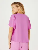 Blusa color rosado con mangas cortas abullonadas y cuello redondo.