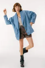 Chaqueta celeste de denim con cuello solapa, corte holgado y cierre frontal con botones dorados.