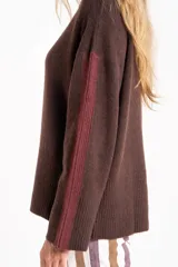 Sweater negro de tejido grueso con cuello alto acanalado. Presenta una franja decorativa en las mangas y el cuello en hilo marrón con brillo (lurex).