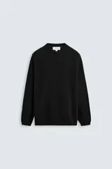 Jersey negro de corte boxy fit, tejido en hilatura con mezcla de algodón y 13% de cashmere. Tiene cuello redondo, manga larga y acabados en rib.