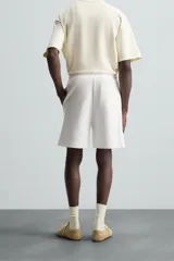 Bermuda color arena de tejido interlock de algodón con elasticidad, corte relaxed fit, cintura elástica ajustable con cordón interior, bolsillos laterales y bolsillo trasero de plastrón.