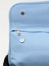 Bandolera azul pastel con correa ancha de tela negra ajustable.