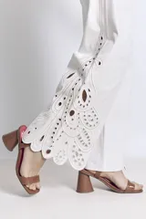 Pantalón blanco de corte ancho con bordados calados en forma de hojas en el ruedo.