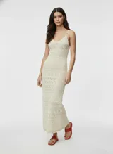 Vestido largo tejido color crudo, con escote en V, breteles finos y diseño calado.