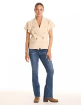 Chaqueta sastrera color beige de la marca Nanette, con cuello con solapa y escote en V. Presenta cierre cruzado con doble abotonadura, manga corta con volado y bolsillos delanteros simulados. El ruedo frontal tiene un acabado en pico y cuenta con forro interno a tono.