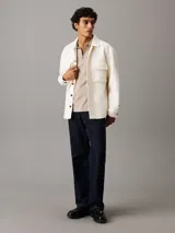 Chomba Calvin Klein color beige con cuello polo y media cremallera. Tiene mangas cortas y un parche de goma con el logo de la marca.