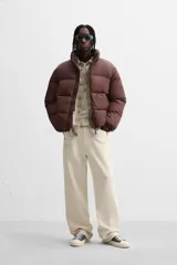 Campera puffer marrón con cuello alto, cierre frontal con cremallera, bolsillos laterales y puños elásticos.