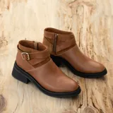 Bota corta de cuero color marrón con cierre lateral, suela de goma negra y hebilla decorativa.