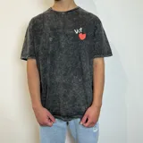 Remera negra con efecto acid wash, corte holgado y estampa frontal con las letras VCP y un corazón rojo.