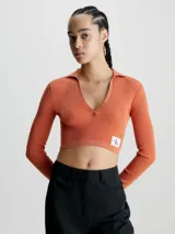 Sweater cropped color naranja de lyocell con textura de canalé, cuello polo en pico, mangas largas e insignia con el monograma de Calvin Klein en el bajo.