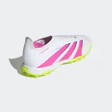 Championes de fútbol Adidas Predator League sin cordones, diseñados para canchas de pasto sintético. Presentan un exterior sintético con tecnología Hybridfeel para un mejor control de la pelota, diseño en color blanco con las tres tiras en fucsia y una suela de caucho estriada en color verde lima.