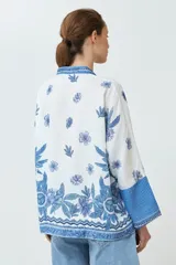 Kimono blanco con estampado floral azul, con mangas 3/4 y cierre frontal con cordón.