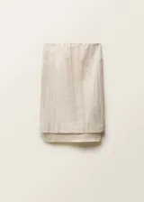 Falda midi color crudo, de corte recto y tiro medio. Presenta un forro interior visible de ramio y cintura con goma elástica.