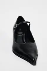 Zapato de cuero negro con tacón kitten, tira delantera con hebilla ajustable y punta fina.