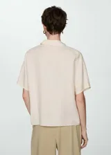 Camisa blanca de lino con cuello clásico, manga corta y cierre frontal con botones.