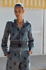Blusa azul con bordados negros, cuello redondo con escote en pico y cordones ajustables terminados en borlas.
