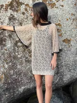 Vestido corto de encaje beige con mangas al sesgo y guarda de caireles negros en el reborde. Incluye vestido básico negro para usar debajo.