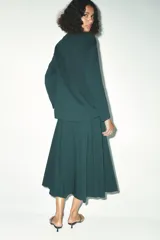 Falda midi verde oscuro con tablas, de tiro alto y cierre trasero con cremallera oculta.