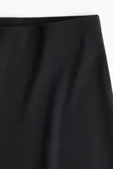 Pantalón negro de punto suave, tiro alto, cintura elástica y piernas amplias.