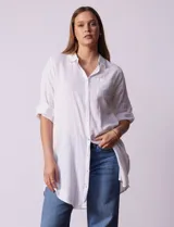 Camisola larga de algodón color blanco, marca Dash. Tiene cuello con solapa, abertura central con botones, bolsillo aplicado en el pecho, mangas regulables con presilla y botón, y bolsillos laterales en la costura.