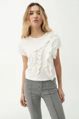 Remera blanca de algodón con cuello redondo y mangas cortas. Presenta volados verticales en el frente.