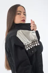 Campera de jean negra con galones decorativos en el pecho y detalles plateados.