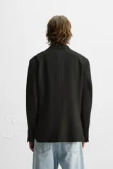 Blazer negro de corte regular fit, confeccionado en tejido con viscosa. Presenta cuello con solapas de muesca, manga larga con puños abotonados, bolsillo de vivo en el pecho, bolsillos de solapa en la cadera, bolsillo interior, aberturas en la espalda y cierre frontal con dos botones.