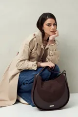 Bolso tipo hobo de cuero sintético negro con panel frontal de gamuza. Tiene correa de hombro ajustable y logo metálico plateado.