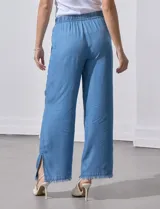 Pantalón celeste de lyocell, corte ancho, con cintura elastizada ajustable con cordón y ruedo desflecado con tajos laterales.