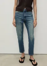 Jeans de tiro alto color azul denim, corte mom fit, con cinco bolsillos, trabillas y cierre frontal con cremallera y botón.