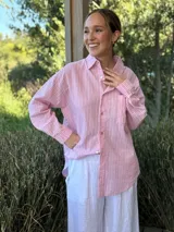 Camisa holgada a rayas verticales color beige y blanco, con cuello clásico, manga larga, bolsillo en el pecho y cierre frontal con botones nacarados.