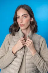 Chaleco acolchado color beige con cierre frontal y cuello alto.