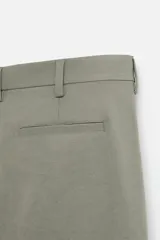 Pantalón chino negro slim fit confeccionado en tejido técnico de secado rápido. Cuenta con bolsillos frontales y traseros de vivo. Cierre frontal con cremallera y botón.