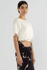 Top color crema de lino y Tencel, con mangas cortas y lazo ajustable en el ruedo.
