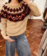 Sweater tejido color beige con cuello redondo y diseño geométrico en tonos marrón, naranja y blanco.