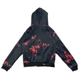 Campera con cierre frontal, capucha forrada con pelo sintético gris y estampado de texto y salpicaduras rojas sobre fondo negro.