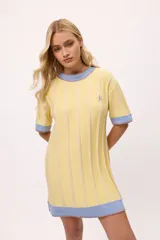 Vestido de tejido de punto, color negro con rayas verticales grises. Tiene cuello redondo y puños y ruedo en color rojo con costuras decorativas en hilo azul. Presenta un pequeño bordado de una letra 'B' estilizada en el pecho.