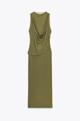 Vestido largo color verde oliva, de tejido de punto con tul, cuello redondo y sin mangas. Presenta un drapeado en la parte superior y cierre lateral con cremallera oculta.