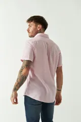 Camisa de manga corta color beige claro, confeccionada en lino y algodón, con cuello abotonado, bolsillo en el pecho y logo bordado. Corte semi slim.