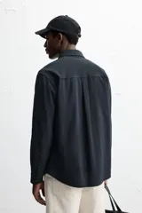 Camisa azul marino de algodón con textura jacquard, corte relaxed fit, cuello solapa, manga larga con puños abotonados y cierre frontal con botones.