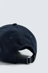 Gorra azul marino con visera y bordado frontal con la frase "Going Through Time Garden District, NOLA" en color crema. Ajuste trasero con hebilla metálica.