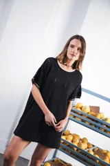 Vestido corto negro con patrón calado cuadrado, cuello redondo y mangas cortas con terminaciones a contratono en blanco.