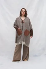 Chal marrón con calce en hombros, abrochadura con alamar de cuero y bolsillos de cuero. Terminación con flecos.