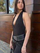 Mono largo negro con escote halter y espalda descubierta. Incluye cinturón ancho de cuero sintético con tachas plateadas.