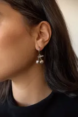 Par de aros plateados con forma de cerezas colgando de un aro pequeño.