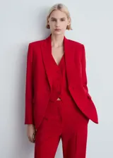 Traje sastrero rojo compuesto por blazer de corte recto con solapas de muesca y cierre de doble botón, chaleco con escote en V y pantalón de vestir de corte recto.