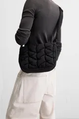 Bandolera negra acolchada de tejido técnico con cierre de cremallera. Tiene dos bolsillos interiores, uno con cremallera. El asa de hombro es ajustable.