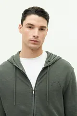 Campera verde militar de felpa con capucha ajustable y cierre frontal. Tiene un pequeño logo estampado en el pecho.