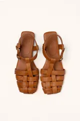 Sandalias franciscanas rojas de cuero con tiras entretejidas y hebilla lateral.