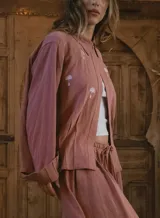 Camisa blanca de lino con bordados dorados de árboles, corte recto, cuello camisero y mangas largas con puños abotonados.